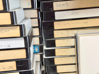 乱雑に積まれたたくさんの古い手書きタイトルのビデオテープ