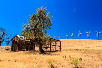 A small house is on a hill with a windmill in the background