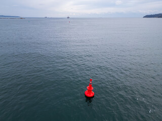 Close-up aerial view of a red navigation buoy floating in the calm waters of the Sea. The buoy...