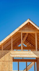 The shot of the wooden frame of the house against a blue sky is perfect for publications about construction, architecture and interior design.