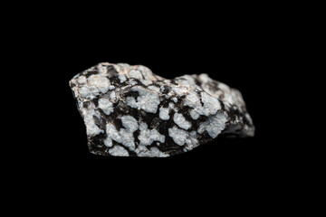 Closeup natural rough snowflake obsidian on dark background. A volcanic rock with cristobalite crystals inclusions. (selective focus)