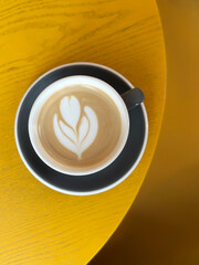 Latte art coffee sitting on modern yellow table in cafe