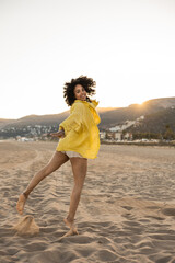 Carefree latin woman dancing on the beach at sunset