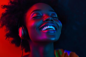 Laughting, close up. African-american woman isolated on dark background in multicolored neon. Listening to music with headphones. Concept of human emotions, facial expression, sales, ad, fashion., Gen