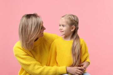 Cute little girl with her mom on pink background. Happy Mother's Day