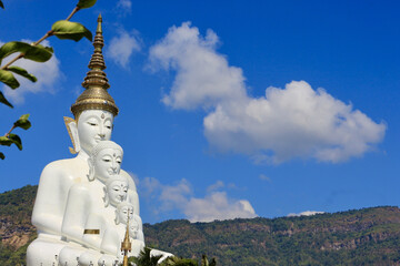 Majestic white Buddha statue against blue sky and mountains