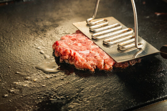 smashing hamburger patty in a flat griddle, smashing or pressing meat patty, smash burger