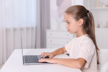 Girl with correct posture using laptop at white desk indoors