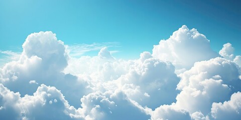 Fluffy white clouds illuminated by sunlight against a bright blue sky with soft gradients in the upper and lower sections of the image