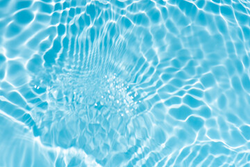 Blue water with ripples on the surface. Defocus blurred transparent blue colored clear calm water surface texture with splashes and bubbles. Water waves with shining pattern texture background.