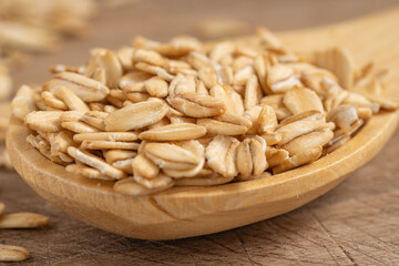 Close-up of rolled oats on a rustic wooden spoon, showcasing a natural and healthy ingredient for breakfast or meal preparation concepts.