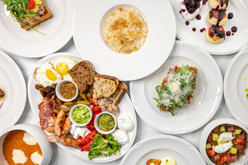 A vibrant assortment of delicious dishes including eggs, smoked salmon, bread, fresh vegetables, and desserts. Perfect for a breakfast or brunch menu.