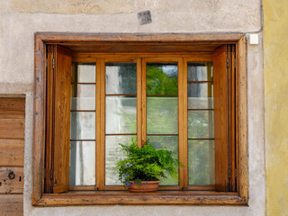 Rustikales Holzfenster mit Pflanze in historischem Gem&auml;uer