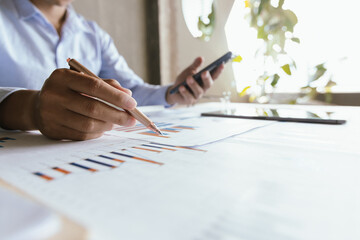 A businessman is analyzing financial data on a laptop surrounded by charts, documents and reports. He focuses on investment planning, budgeting and tax strategies for economic success.