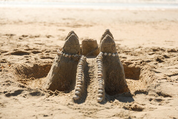 Sandburg mit Muschelverzierung am Strand