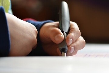 Left handed kid writing with an Pen, macro view