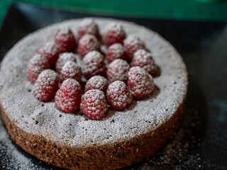 Chocolate cake topped with raspberries and dusted with powdered sugar