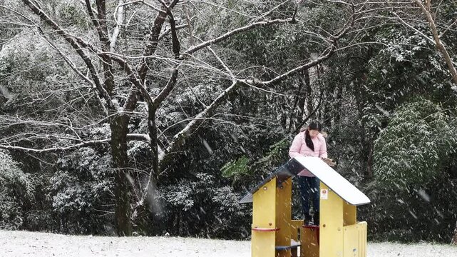 冬の公園で楽しく雪遊びしている小学生の女の子の様子