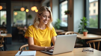 Fototapeta premium Blonde Young Professional Typing on a Laptop in a Cozy Cafe, Representing Modern Work Trends and Digital Innovation