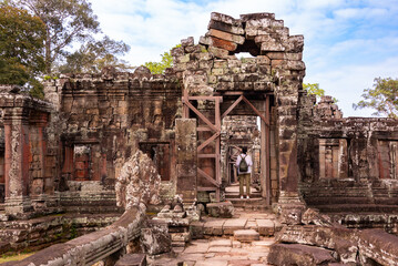 Naklejka premium Tourist entering Angkor ancient temple ruins in Cambodia