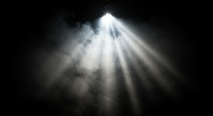 Obraz premium Bright light shines through smoke on black background. Ethereal mist creates magical glow. God’s rays beam down in surreal fantasy stage lighting atmosphere