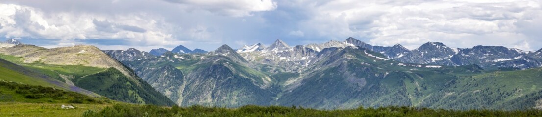 panorama of mountains and snow-capped peaks in eastern kazakhstan with clouds in the sky
