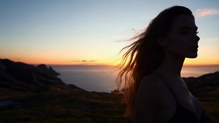 Beautiful sunset silhouette of a woman on rocky beach at dusk