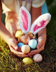 Baby with basket full of colorful eggs. Easter egg hunt.
