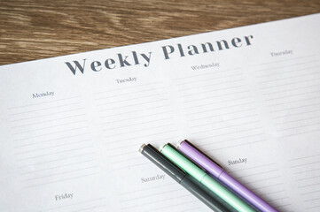 Weekly planner on a wooden desk with colorful pens ready for writing, concept of organization and productivity1