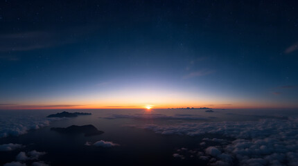 Fototapeta premium A wide-angle view of the night sky, where stars sparkle above faraway mountains and scattered clouds. The setting sun in the background paints the horizon in warm hues, casting elongated shadows acros