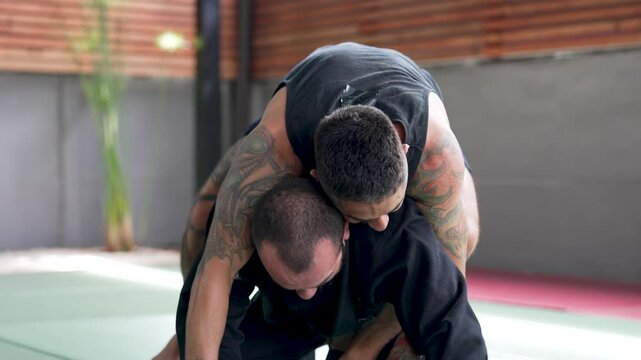 Two jiu-jitsu athletes practicing grappling and submission holds on a training mat