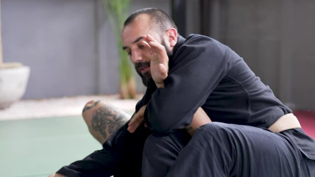 Two male athletes practice jiu-jitsu grappling techniques on a training mat