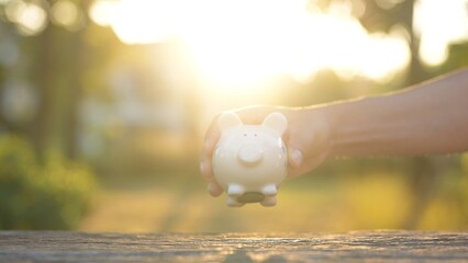 Saving for the Future A Hand Holding a Piggy Bank at Sunset Personal Finance Outdoor Setting...