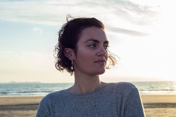 Portrait of a young woman with curly hair at sunset on the beach