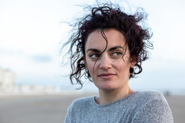 Portrait of a young woman with curly hair at sunset on the beach