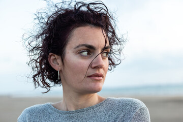 Portrait of a young woman with curly hair at sunset on the beach