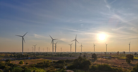 Obraz premium Beautiful landscape group of wind turbines standing in field for sustainable energy on sunset