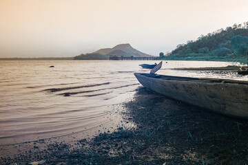 Obraz premium Infrared photography, a wooden boat rests on the sandy shore of a lake, its bow pointed towards the water.