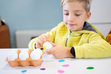 Child painting easter eggs at home getting ready for easter celebration