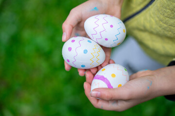Child holding three hand-decorated easter eggs in nature