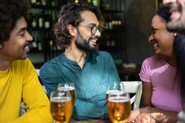 Happy multiracial business colleagues having a drink after work at brewery bar. Friendship concept