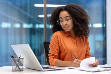 Serious focused woman doing paperwork inside office. Accountant financier signing contracts and...