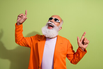 Photo of funny extravagant man hjave fun dancing wear orange suit isolated on green color background
