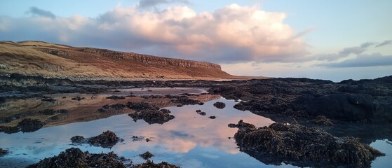 Serene coastal landscape with reflections during twilight near rocky cliffs