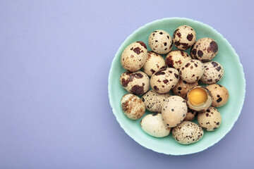 Quail eggs in bowl on purple background