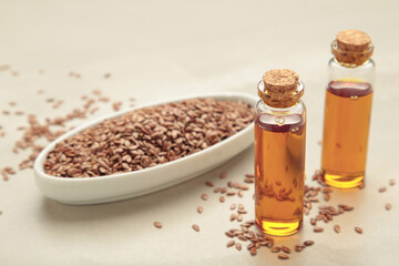 Flaxseeds with flaxseed oil in glass bottle on light background.