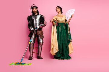 Fototapeta premium Knight and noblewoman in medieval costumes interacting with humor on pink background