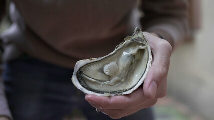 Person showing oyster to camera with knife © Marco