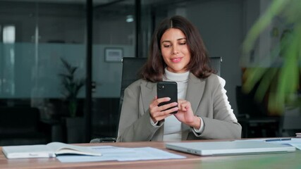 Young Indian business woman manager ceo using cell phone mobile app laptop. Smiling Latin Hispanic mature female businesswoman holding smartphone in office trading, reading, working online. Copy space - Powered by Adobe