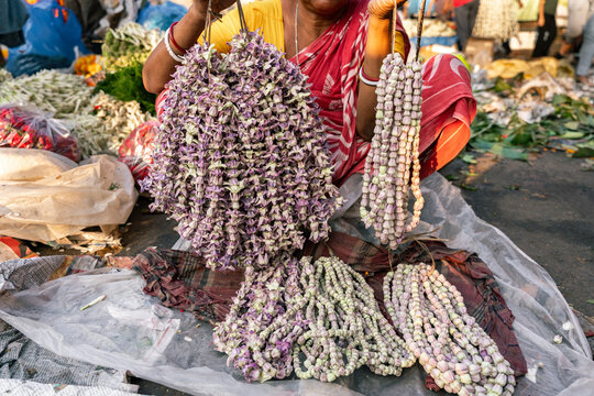 Woman in traditional sari clothes selling garlands in a flower street market in India